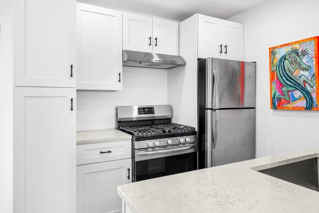 kitchen featuring light stone counters, white cabinetry, and stainless steel appliances