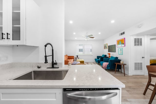 kitchen featuring light stone counters, white cabinets, stainless steel dishwasher, light hardwood / wood-style floors, and sink