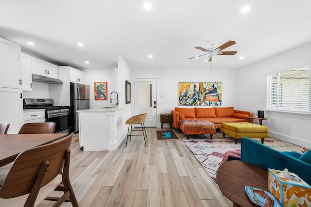 living room with sink, light wood-type flooring, and ceiling fan