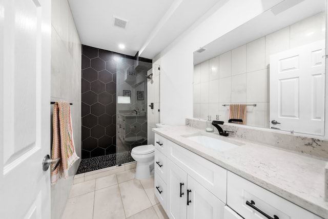 bathroom featuring tile walls, vanity, a tile shower, and tile patterned flooring