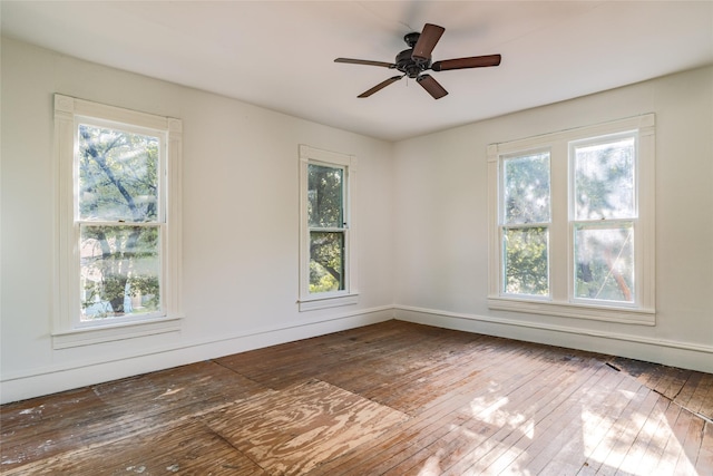 empty room with plenty of natural light, dark hardwood / wood-style floors, and ceiling fan