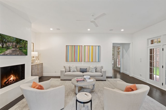 living room featuring ceiling fan and dark hardwood / wood-style flooring