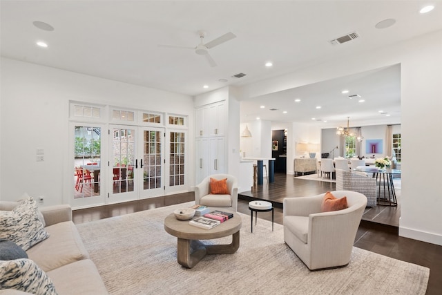 living room featuring dark wood-type flooring, ceiling fan with notable chandelier, and french doors