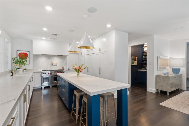 kitchen with double oven range, dark hardwood / wood-style floors, white cabinets, and a center island