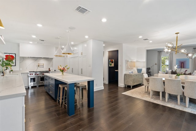 kitchen featuring white cabinets, dark hardwood / wood-style flooring, a kitchen island, decorative light fixtures, and double oven range