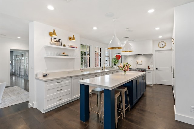 kitchen with hanging light fixtures, a kitchen breakfast bar, white cabinets, and dark hardwood / wood-style floors