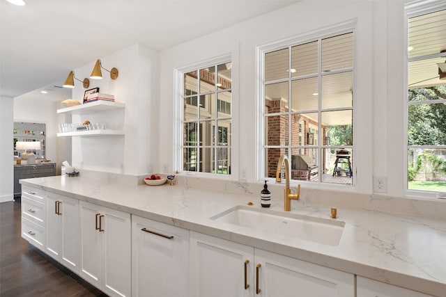 kitchen featuring sink, white cabinetry, light stone counters, and dark wood-type flooring