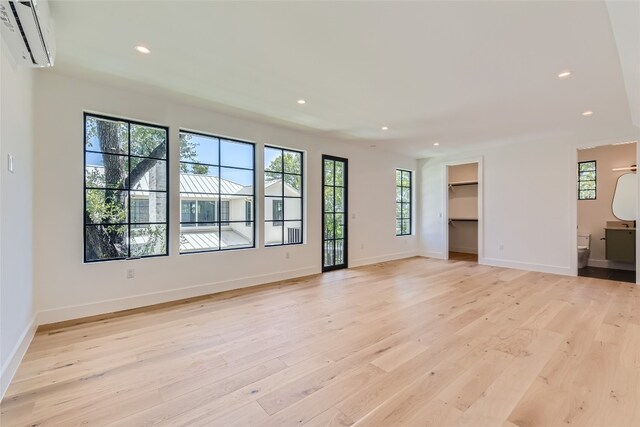 unfurnished living room featuring light wood-type flooring and an AC wall unit