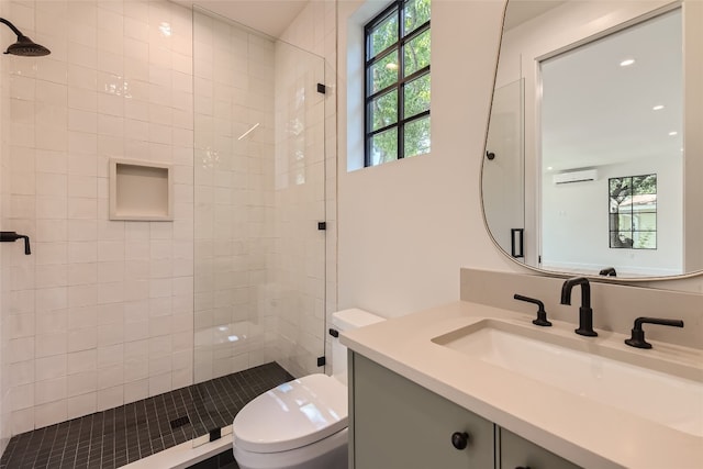 bathroom with vanity, toilet, and tiled shower