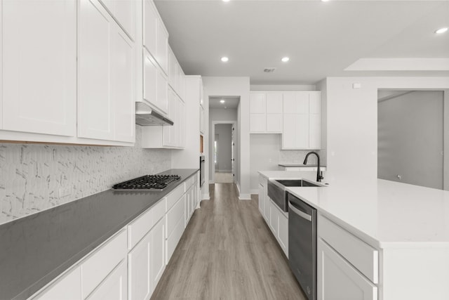 kitchen with white cabinetry, sink, tasteful backsplash, light hardwood / wood-style flooring, and appliances with stainless steel finishes