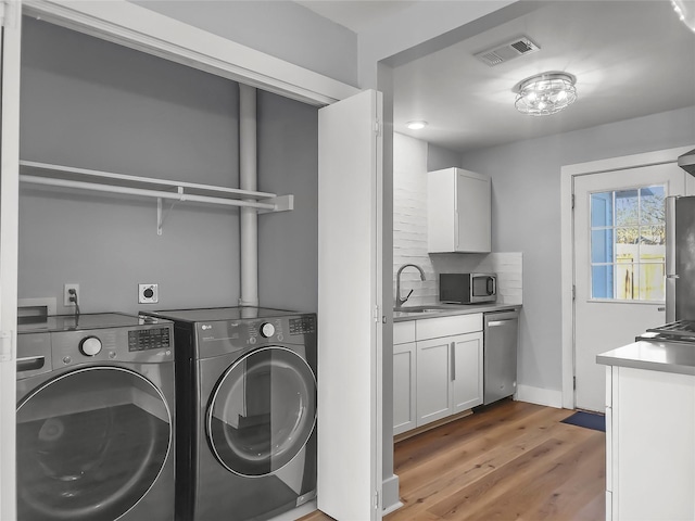 washroom featuring hardwood / wood-style flooring, sink, and washing machine and clothes dryer