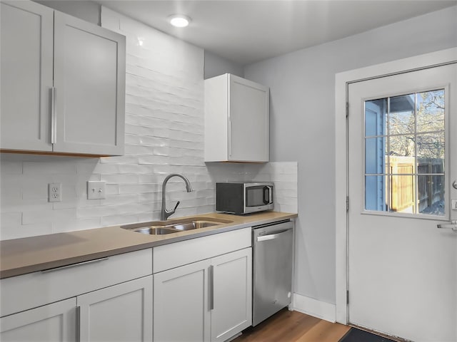 kitchen featuring white cabinetry, sink, backsplash, and appliances with stainless steel finishes