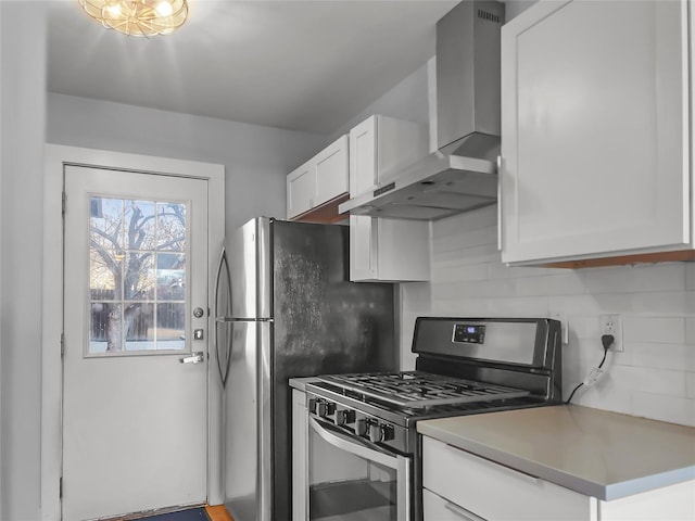 kitchen featuring white cabinetry, backsplash, stainless steel gas range oven, and wall chimney exhaust hood