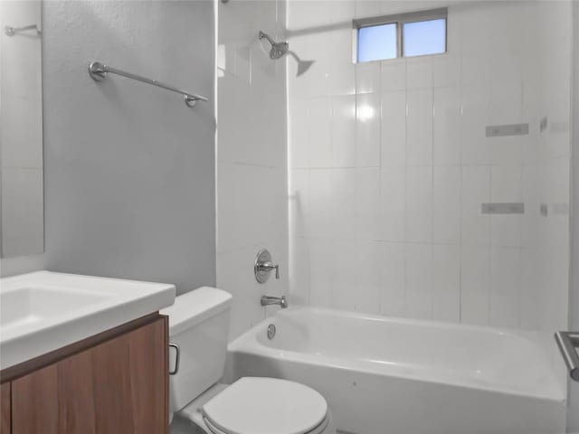 full bathroom featuring vanity, tiled shower / bath, and toilet