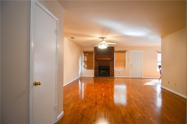 unfurnished living room featuring a fireplace, wood-type flooring, and ceiling fan