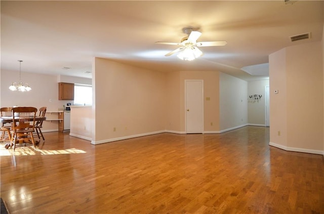 unfurnished room with ceiling fan with notable chandelier and wood-type flooring