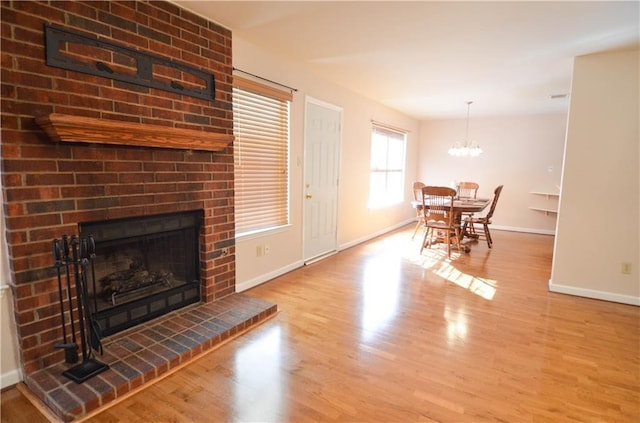 living room with a brick fireplace, a chandelier, and light hardwood / wood-style flooring