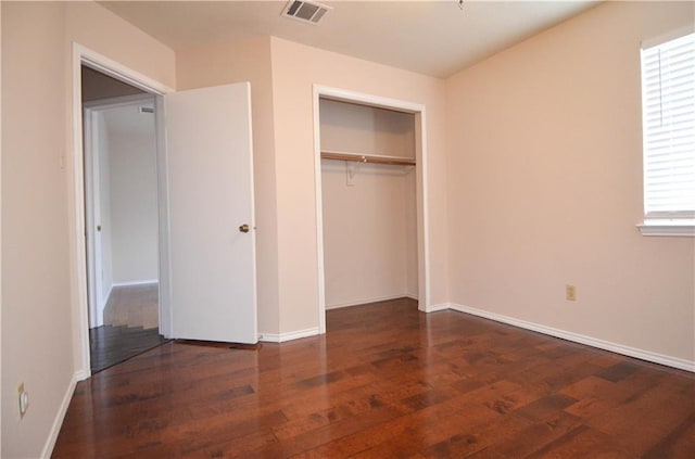 unfurnished bedroom featuring dark hardwood / wood-style flooring and a closet