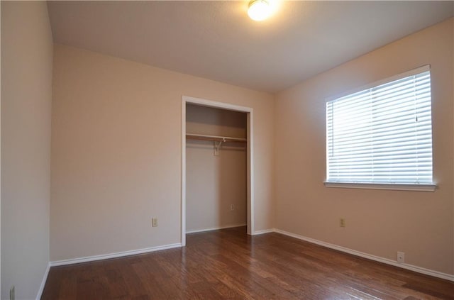 unfurnished bedroom featuring dark wood-type flooring and a closet