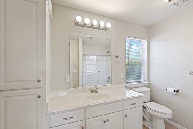 bathroom with tile patterned flooring, vanity, toilet, and walk in shower