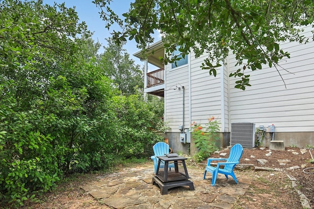 view of patio featuring central AC, a balcony, and a fire pit