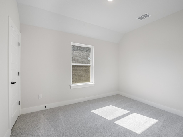 carpeted spare room featuring vaulted ceiling