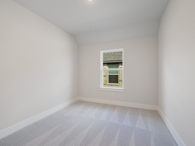 carpeted spare room with lofted ceiling