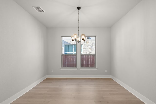 unfurnished dining area featuring light hardwood / wood-style flooring and an inviting chandelier