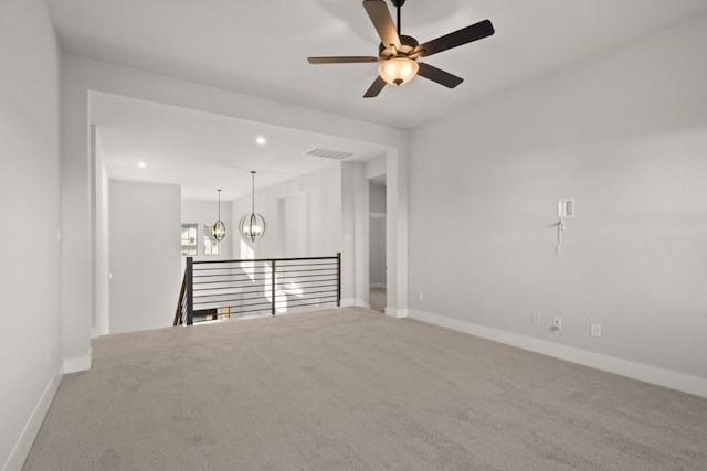 carpeted spare room with ceiling fan with notable chandelier