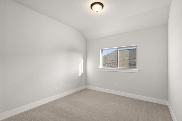 unfurnished room featuring carpet and lofted ceiling