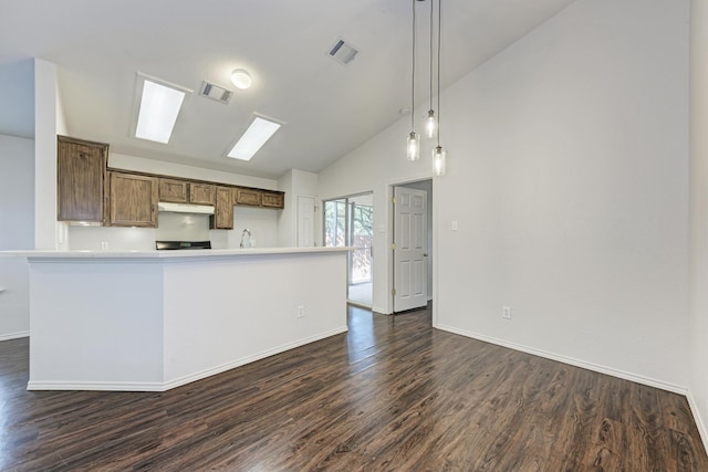 kitchen featuring pendant lighting, sink, vaulted ceiling with skylight, dark hardwood / wood-style flooring, and kitchen peninsula