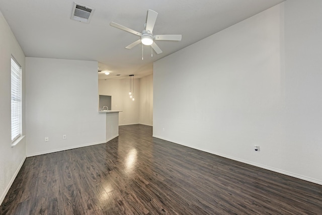 unfurnished room featuring a healthy amount of sunlight, ceiling fan, and dark wood-type flooring