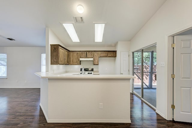 kitchen with vaulted ceiling, kitchen peninsula, sink, and dark wood-type flooring