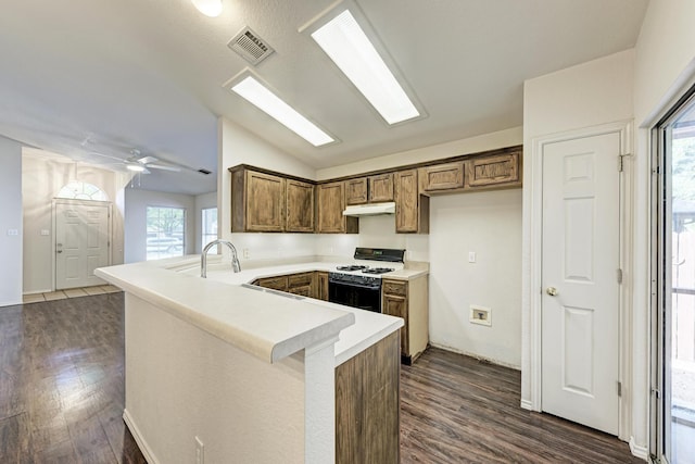 kitchen featuring ceiling fan, dark hardwood / wood-style flooring, kitchen peninsula, and range with gas cooktop