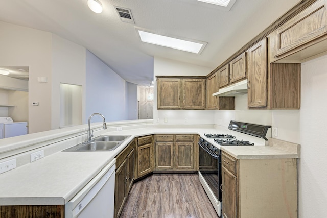 kitchen with washing machine and clothes dryer, sink, gas range oven, white dishwasher, and lofted ceiling