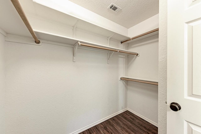 walk in closet with dark wood-type flooring