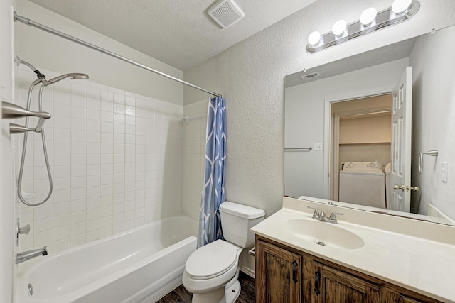 full bathroom featuring shower / bath combo, vanity, a textured ceiling, washing machine and clothes dryer, and toilet