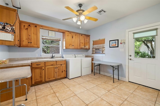 washroom with cabinets, sink, ceiling fan, independent washer and dryer, and light tile patterned floors