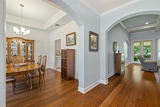 dining area with french doors, ornamental molding, dark wood-type flooring, and a chandelier