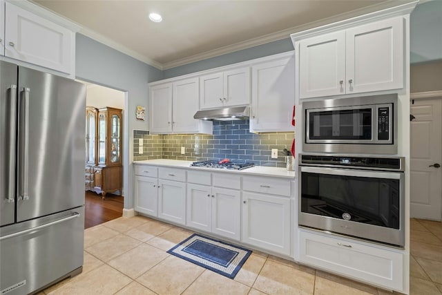 kitchen featuring light tile patterned floors, white cabinetry, ornamental molding, and appliances with stainless steel finishes