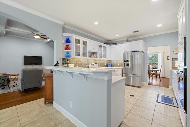 kitchen featuring light tile patterned floors, white cabinetry, kitchen peninsula, and appliances with stainless steel finishes