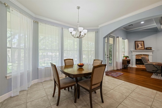 tiled dining space featuring an inviting chandelier, a healthy amount of sunlight, and ornamental molding