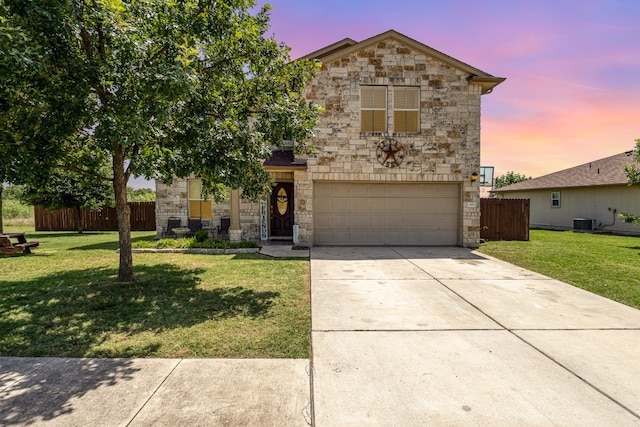 view of front of home featuring a garage, a lawn, and central AC