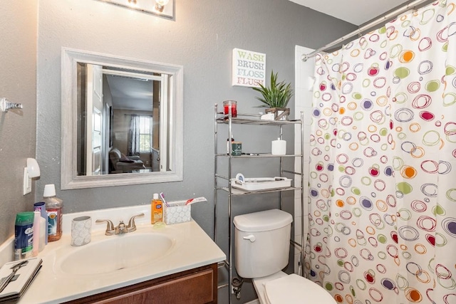 bathroom with curtained shower, vanity, and toilet