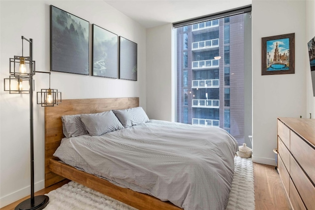 bedroom with a wall of windows and light hardwood / wood-style flooring