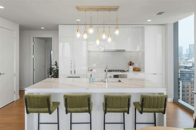 44 E Ave Unit 1507, Austin, TX 78701 - kitchen with modern cabinets, white cabinetry, decorative backsplash, a kitchen breakfast bar, and plenty of natural light