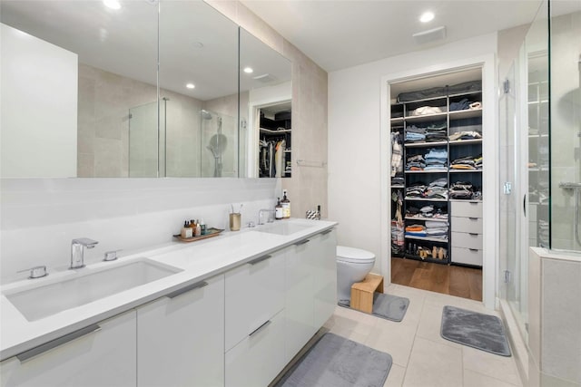 44 E Ave Unit 1507, Austin, TX 78701 - bathroom with a walk in closet, double vanity, a shower stall, toilet, and tile patterned floors