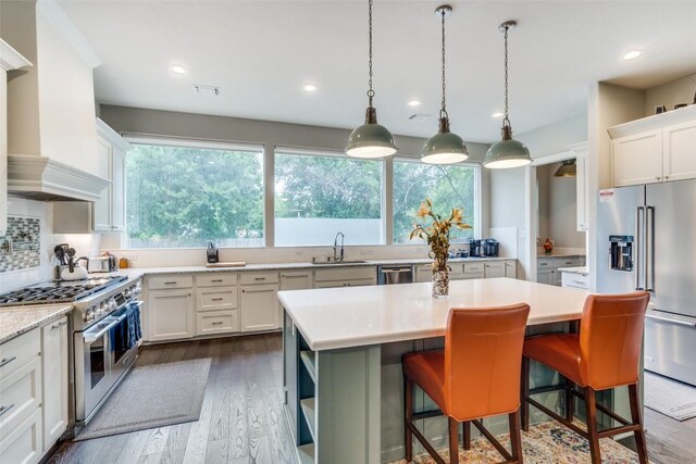 kitchen with a kitchen bar, sink, premium range hood, a kitchen island, and high quality appliances