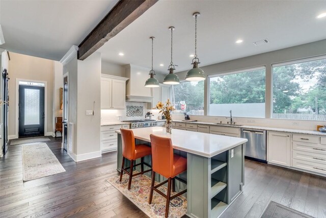 kitchen featuring stainless steel appliances, sink, white cabinetry, a center island, and dark wood-type flooring