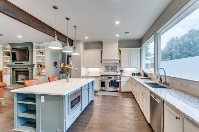 kitchen featuring stainless steel appliances, a fireplace, white cabinetry, dark hardwood / wood-style flooring, and custom range hood